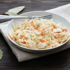 Chrupiąca surówka z białej kapusty i marchewki, jak w restauracji, podana na talerzu z widelcem.