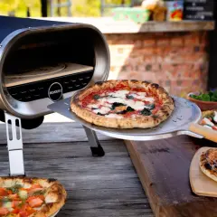Piec do pizzy z otwartą komorą, na stole leżą świeżo upieczone pizze.
