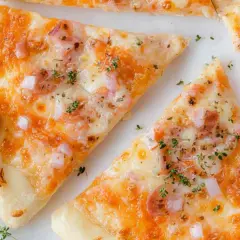 Kawałki pysznej pizzy z twarogu, posypane ziołami i kawałkami cebuli.