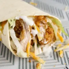 Klasyczny mcwrap z chrupiącym kurczakiem, serem i warzywami, polany sosem. Idealny na szybki posiłek, choć warto pamiętać o jego kcal.
