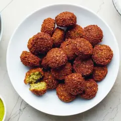 Talerz pełen chrupiących kuleczek falafela, które są idealną przekąską. Obok sos tahini i marynowana rzepa.