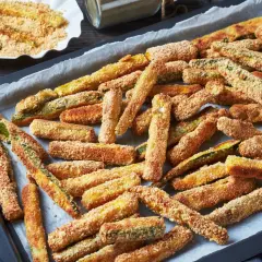 Chrupiące frytki z cukinii w panierce na blasze do pieczenia.