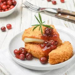 Chrupiący ser w panierce z żurawiną i rozmarynem, podany na białym talerzu. Idealna przekąska na zimowe wieczory.