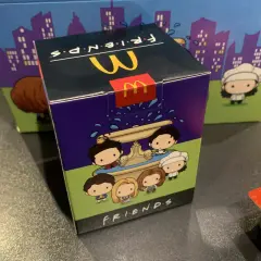 Pudełko McDonald's z motywem Friends, przedstawiające urocze postacie z serialu przy fontannie.