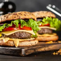 Dwa soczyste hamburgery z serem, sałatą i pomidorem, podane z frytkami.