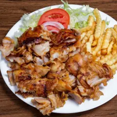 Talerz z kurczakiem gyros, frytkami, sałatą, pomidorem i cebulą.