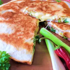 Złocista tortilla z jajkiem, serem i szynką, usmażona na patelni, z dodatkiem szczypiorku i papryczki.