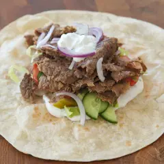 Kebab w tortilli z mięsem, warzywami, sosem i cebulą.
