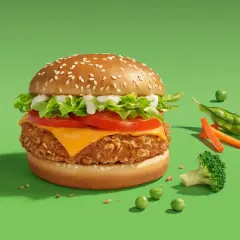 Pyszny wege burger McDonald's z chrupiącym kotletem, serem, pomidorem i sałatą. Obok świeże warzywa: groszek, marchewka i brokuł.