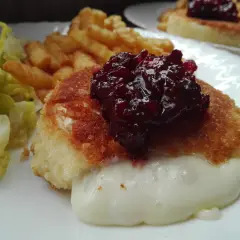Pyszny camembert w panierce, z rozpływającym się serem, podany z frytkami i sałatką.