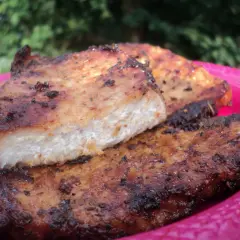 Grillowany schab na różowym talerzu, z widocznym przekrojem mięsa.