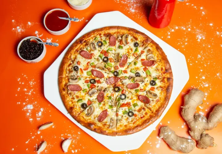 Apetyczna pizza z kiełbasą, pieczarkami i papryką. Widać też sosy i imbir, sugerujące ciekawe pizza składniki.