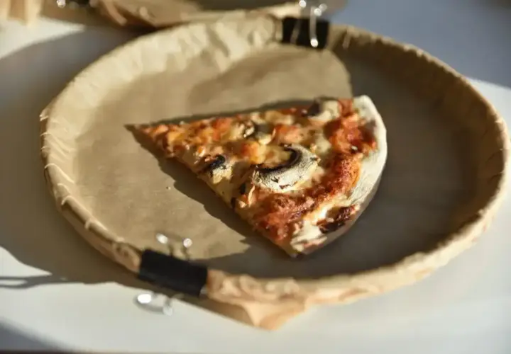 Kawałek pizzy z pieczarkami na papierowym talerzu. Zastanawiasz się nad pizza kcal?
