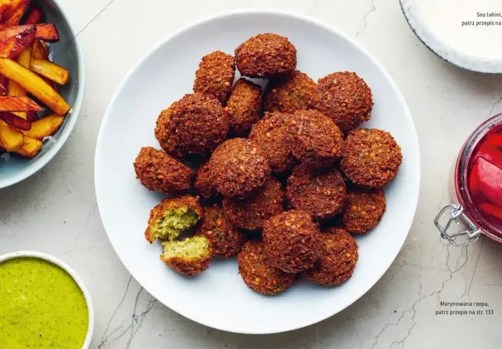 Talerz pełen chrupiących kuleczek falafela, które są idealną przekąską. Obok sos tahini i marynowana rzepa.