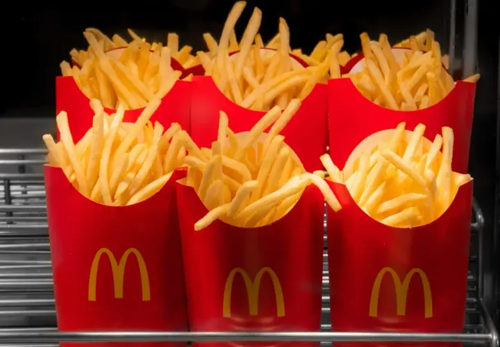 Kilka czerwonych opakowań McDonald's wypełnionych średnimi frytkami.