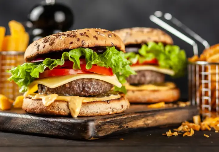 Dwa soczyste hamburgery z serem, sałatą i pomidorem, podane z frytkami.