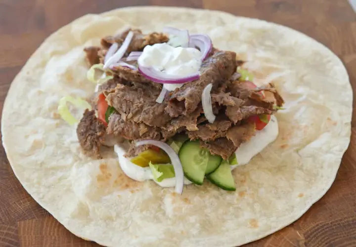 Kebab w tortilli z mięsem, warzywami, sosem i cebulą.