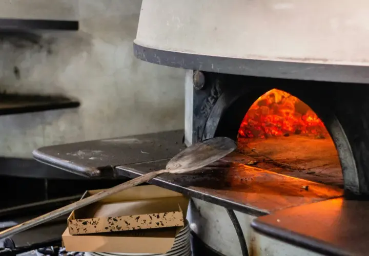 Piec do pizzy z żarem i łopatą do pizzy.
