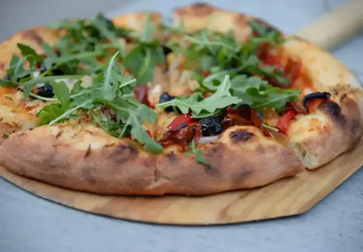 Pyszna pizza domowa na blachę, z ciasta na świeże drożdże, z rukolą i oliwkami.