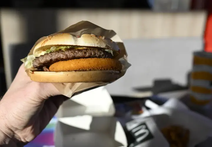 Dłoń trzyma burgera McDouble z podwójnym kotletem i chrupiącą warstwą.