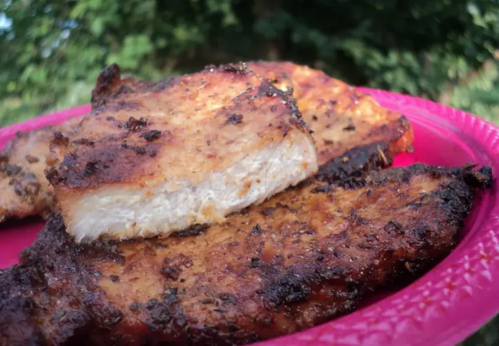 Grillowany schab na różowym talerzu, z widocznym przekrojem mięsa.