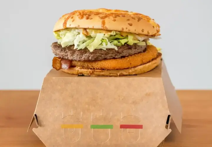 Drwal z chrzanem, czyli soczysty burger z chrupiącą panierką i wołowiną, na papierowym opakowaniu.