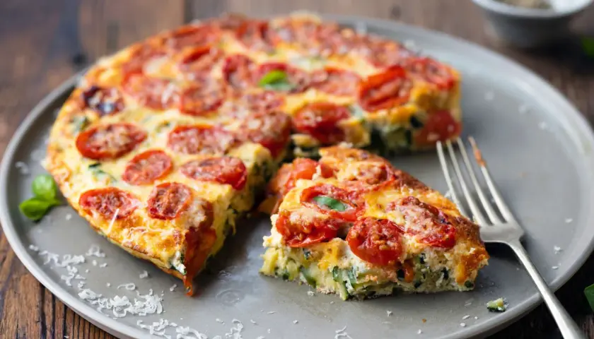 Pyszna pizza z cukinii z pomidorkami i bazylią na talerzu, gotowa do podania.
