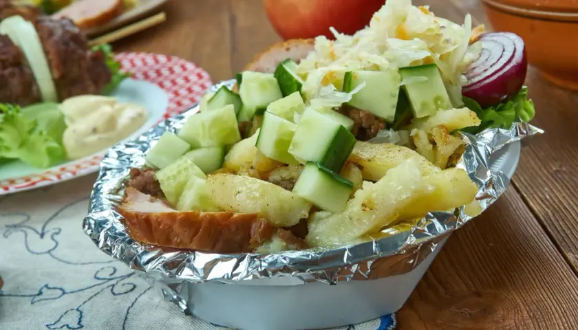 Kapsalon z frytkami, mięsem, serem, ogórkiem i surówką w folii aluminiowej.
