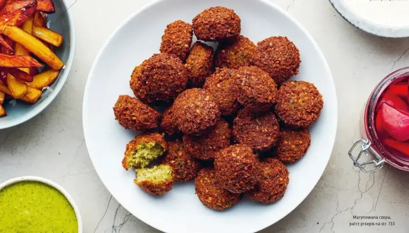 Talerz pełen chrupiących kuleczek falafela, które są idealną przekąską. Obok sos tahini i marynowana rzepa.