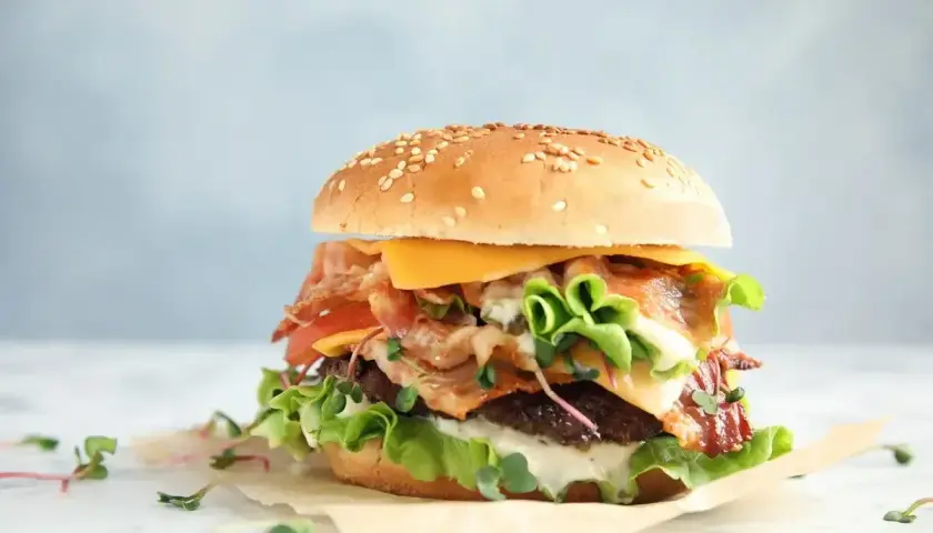 Pyszny burger z bekonem, serem i świeżymi warzywami. Zastanawiasz się, ile kalorii ma wieśmac? Ten wygląda na sycący!