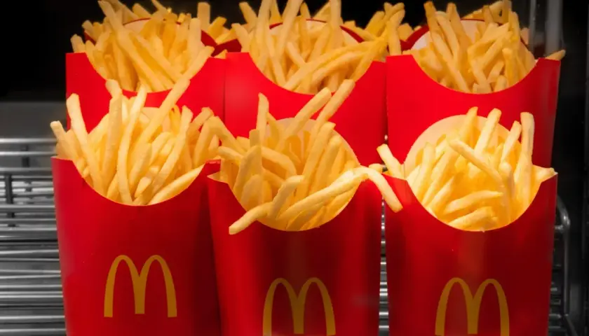 Kilka czerwonych opakowań McDonald's wypełnionych średnimi frytkami.