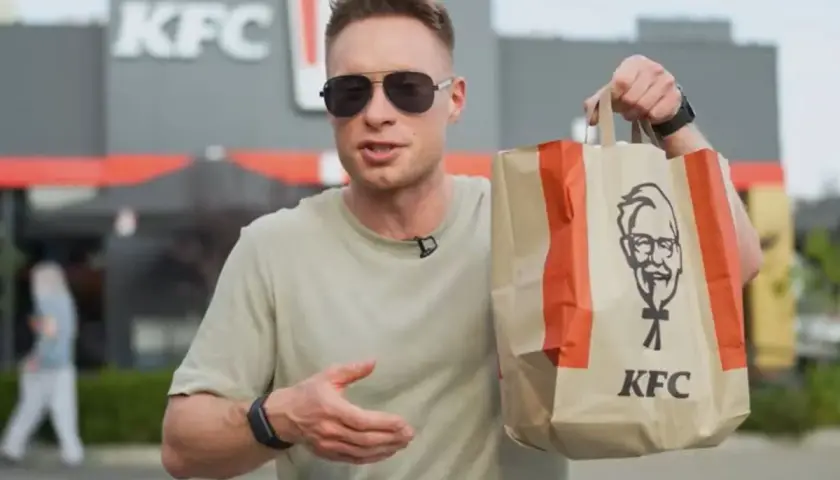 Mężczyzna trzyma torbę z KFC, zastanawiając się nad kalorycznością frytek.