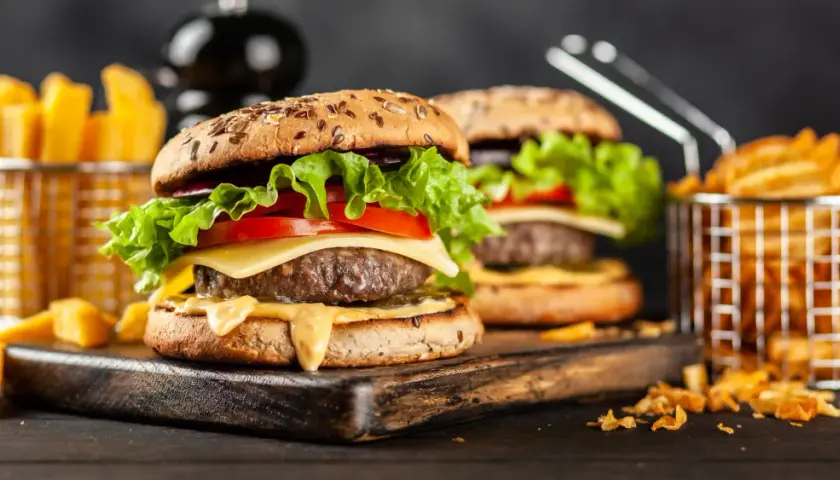 Dwa soczyste hamburgery z serem, sałatą i pomidorem, podane z frytkami.