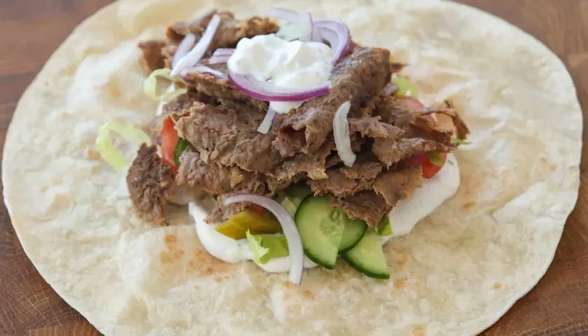 Kebab w tortilli z mięsem, warzywami, sosem i cebulą.
