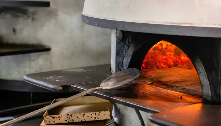 Piec do pizzy z żarem i łopatą do pizzy.