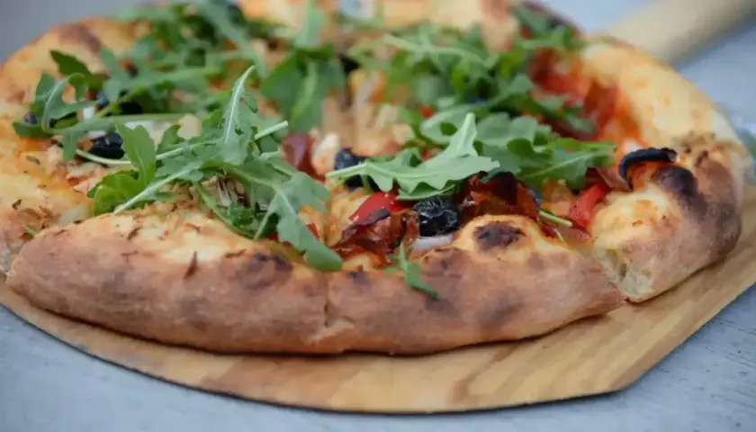Pyszna pizza domowa na blachę, z ciasta na świeże drożdże, z rukolą i oliwkami.