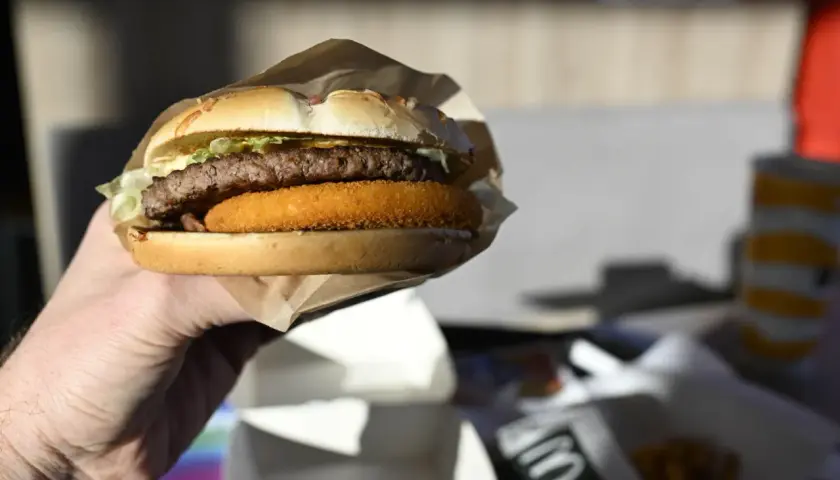 Dłoń trzyma burgera McDouble z podwójnym kotletem i chrupiącą warstwą.