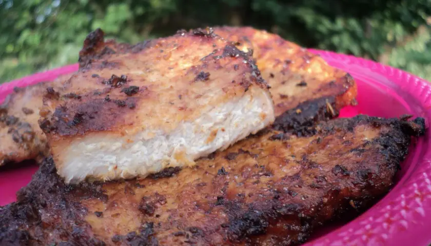 Grillowany schab na różowym talerzu, z widocznym przekrojem mięsa.