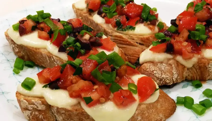 Bruschetta z pomidorami i mozzarellą, idealna na szybki przepis. Chrupiące grzanki z roztopionym serem, świeżymi pomidorami i szczypiorkiem.