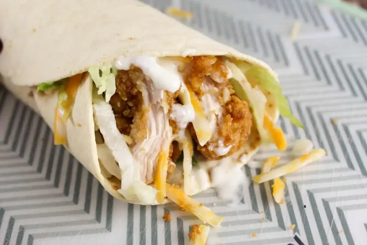 Klasyczny mcwrap z chrupiącym kurczakiem, serem i warzywami, polany sosem. Idealny na szybki posiłek, choć warto pamiętać o jego kcal.