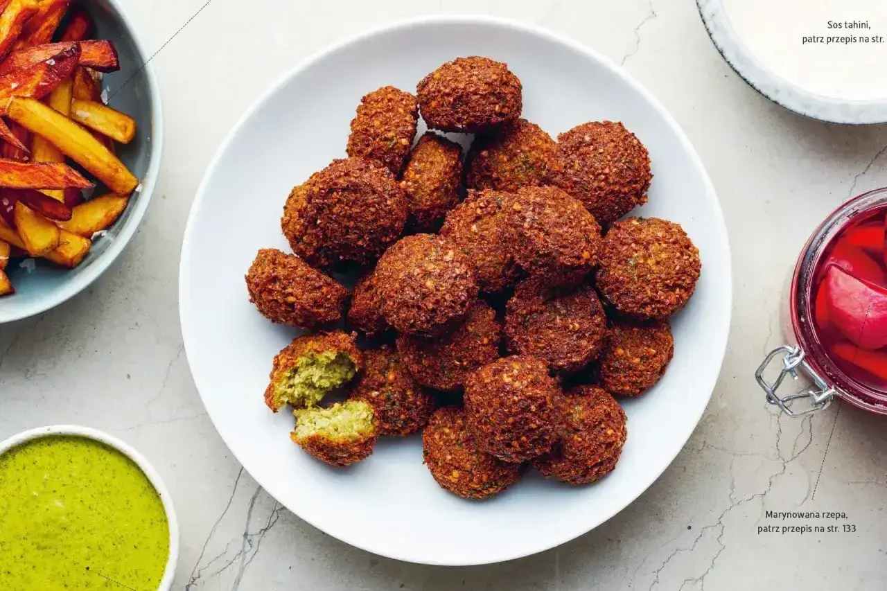 Talerz pełen chrupiących kuleczek falafela, które są idealną przekąską. Obok sos tahini i marynowana rzepa.