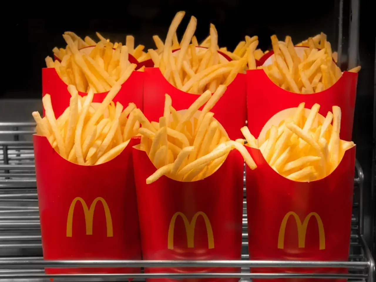 Kilka czerwonych opakowań McDonald's wypełnionych średnimi frytkami.
