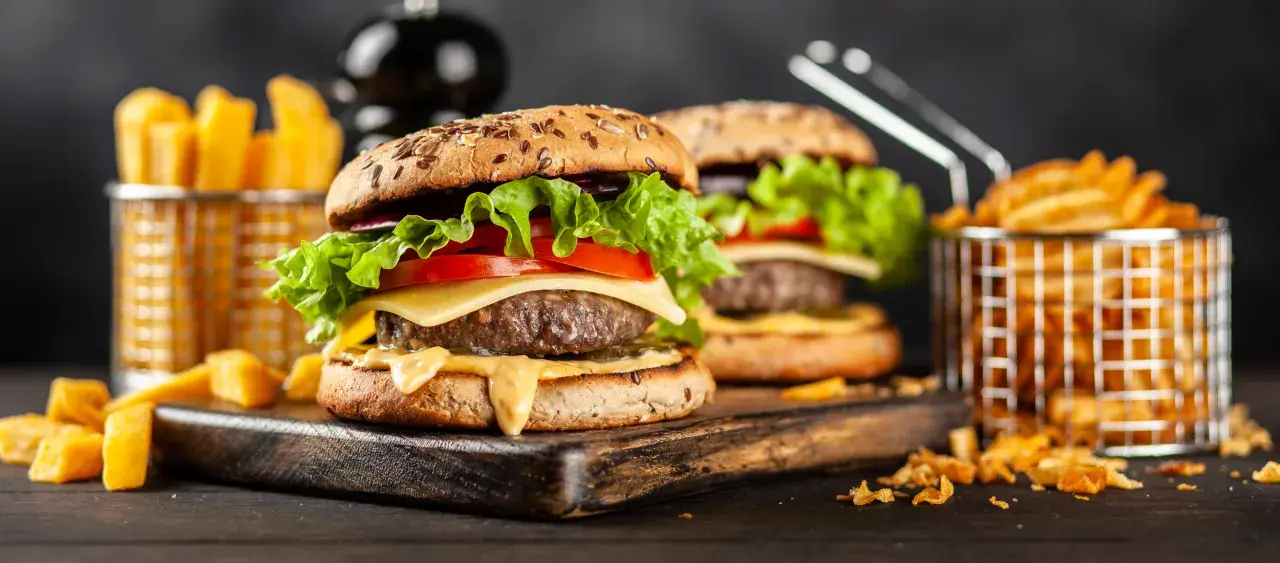 Dwa soczyste hamburgery z serem, sałatą i pomidorem, podane z frytkami.
