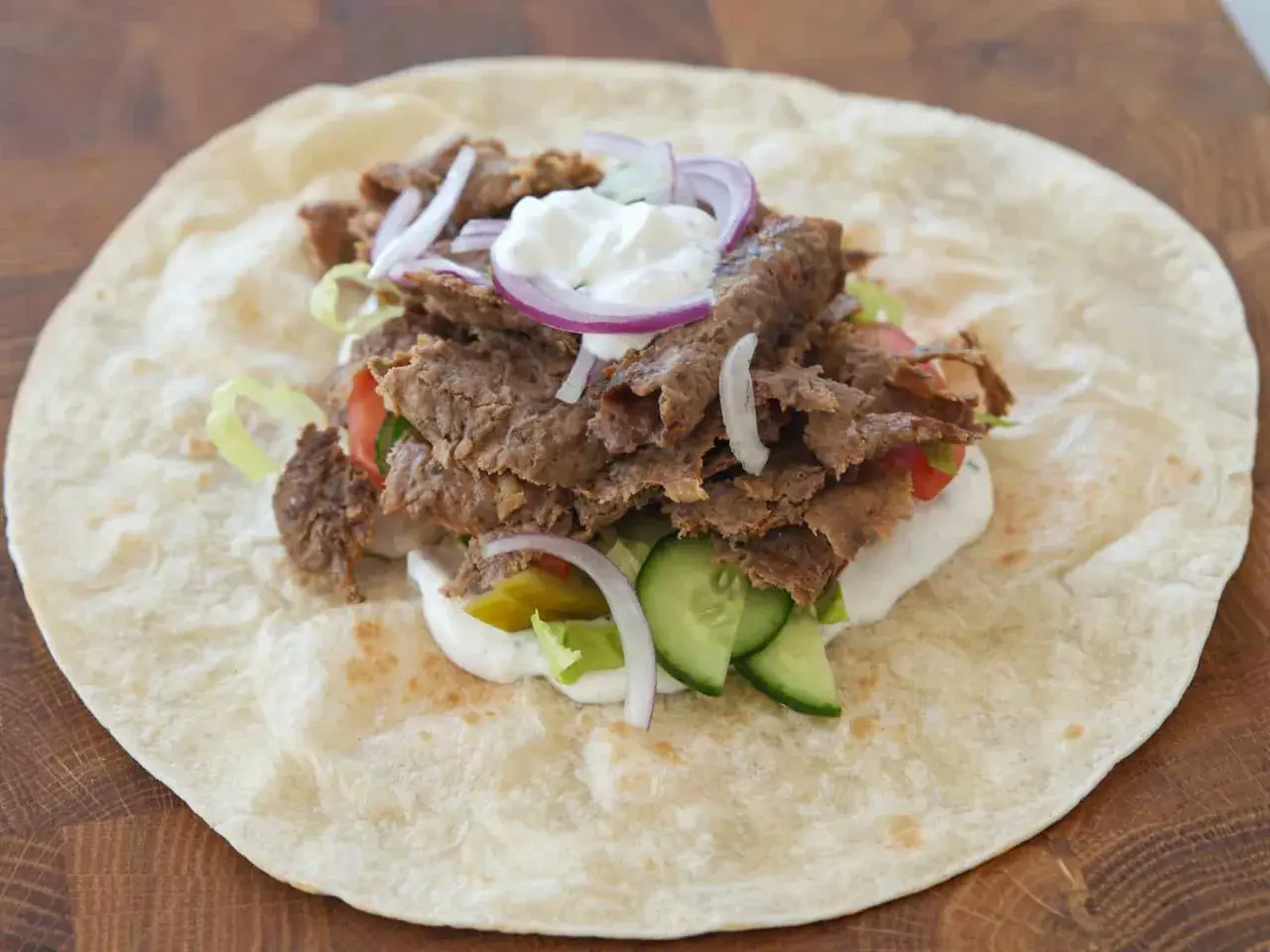 Kebab w tortilli z mięsem, warzywami, sosem i cebulą.