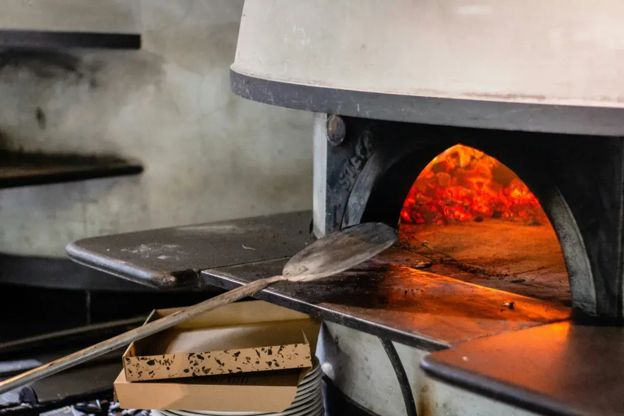 Piec do pizzy z żarem i łopatą do pizzy.