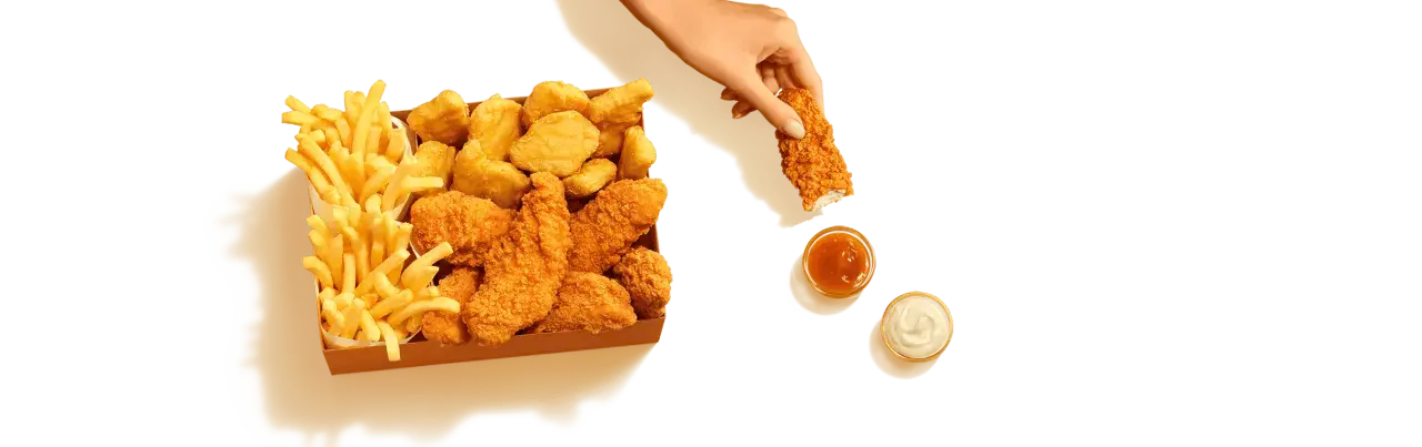 Pudełko McDonald's z kurczakiem, frytkami i sosami.