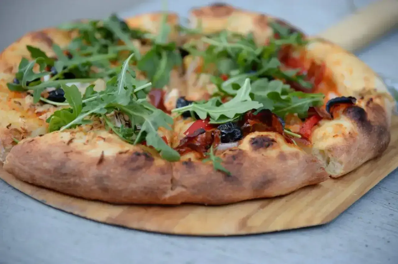 Pyszna pizza domowa na blachę, z ciasta na świeże drożdże, z rukolą i oliwkami.
