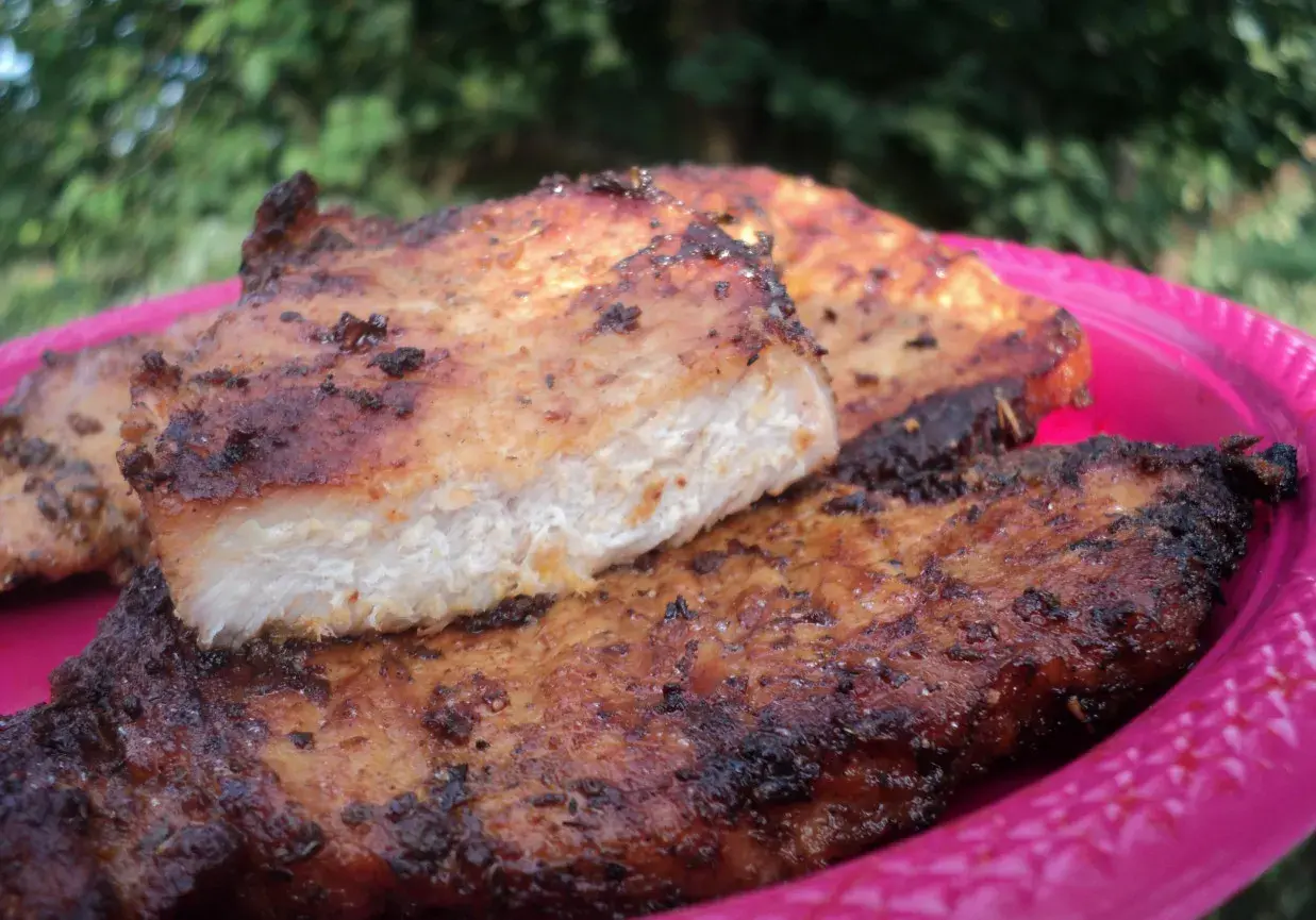 Grillowany schab na różowym talerzu, z widocznym przekrojem mięsa.
