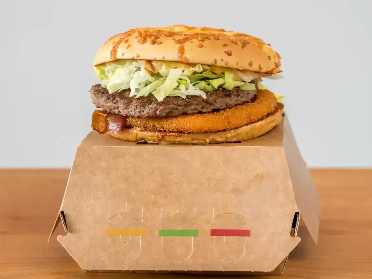 Drwal z chrzanem, czyli soczysty burger z chrupiącą panierką i wołowiną, na papierowym opakowaniu.