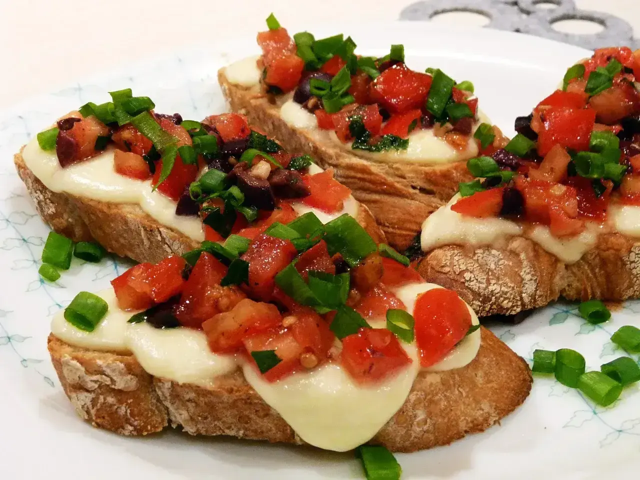 Bruschetta z pomidorami i mozzarellą, idealna na szybki przepis. Chrupiące grzanki z roztopionym serem, świeżymi pomidorami i szczypiorkiem.